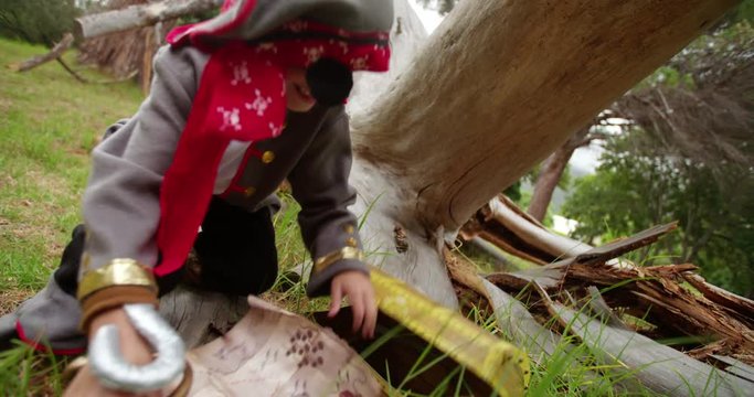Boy dressing up pirate finding  treasure chest under tree