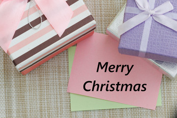 Gift boxes on a table with word Merry Christmas on a piece of paper