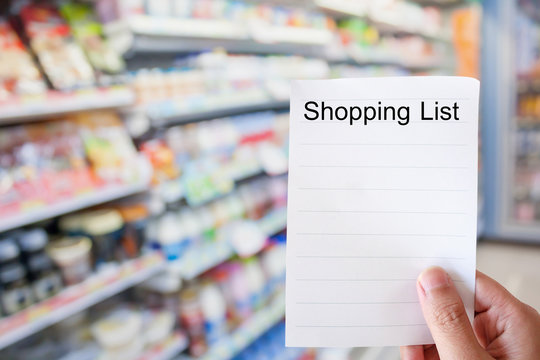 hand holding shopping list paper with convenience store shelves