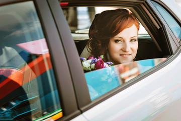 Beautiful Bride in Car on wedding day looking at camera