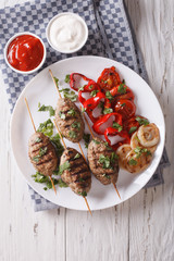 kofta kebab with grilled vegetables on a plate and sauce. vertical top view 

