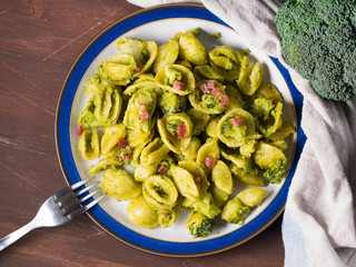 Italian orecchiette pasta with broccoli, bacon and parmesan on dark wooden background