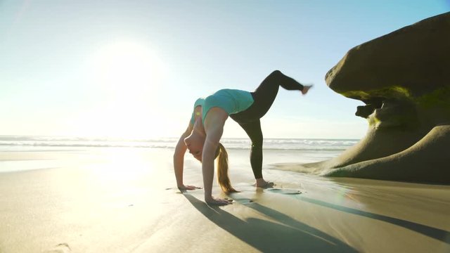 Happy young woman practicing yoga on the beach at sunset. Healthy active lifestyle concept. 4K
