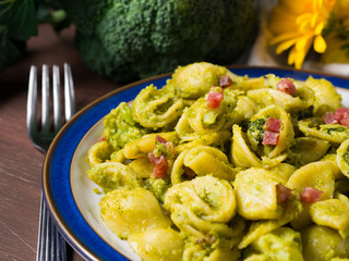 Italian orecchiette pasta with broccoli, bacon and parmesan on dark wooden background