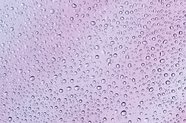 Drops on the glass, lilac-pink background