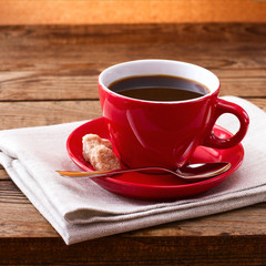 Coffee cup and saucer on tablecloth on wooden table. Dark background. Coffee concept. Selective focus.