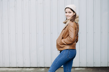 Young beautiful girl in a leather jacket posing at wall background