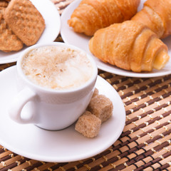Cup of coffee, sweets, croissant and cane sugar cubes, square. Coffee concept. Selective focus.
