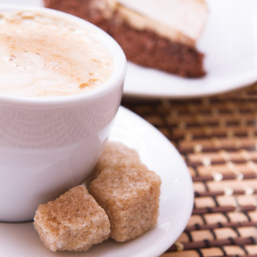 Cup of coffee, sweets and cane sugar cubes, square. Coffee concept. Selective focus.