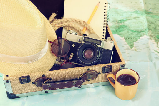 traveling concept. camera, cup of coffee, sunglasses, fedora hat and notebook. vintage style filtered. selective focus
