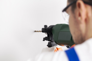 Young man drilling hole in wall