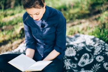 Girl reading a book in nature/ Shot of young beautiful woman who reading a book in nature.