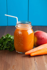 Healthy carrot apple smoothie in a jar on blue wooden background