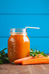 Healthy carrot apple smoothie in a jar on blue wooden background