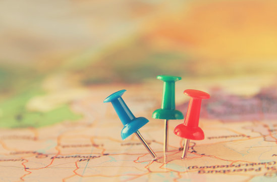 pins attached to map, showing location or travel destination . retro style image. selective focus.
