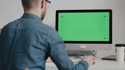 Caucasian worker typing on keyboard and looking at green screen - Powered by Adobe