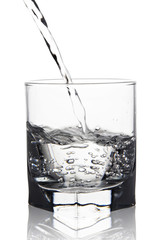 Water with air bubbles pouring into glass with its reflection, c