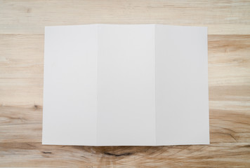 Trifold white template paper on wood texture..