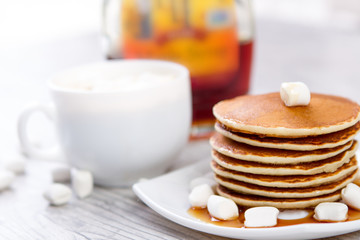 Tasty pancake on a white plate, wooden background, maple syrup