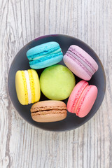 collection of colorful French macarons are next to each other around the plates, top view