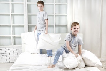 Young children playing on the bed. Pillow fight
