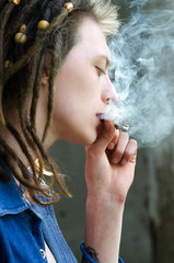 Portrait of young man smoking marijuana through the pipe