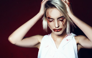 gothic strange girl blonde vampire blood halloween. in the studio on a red background. beauty shot