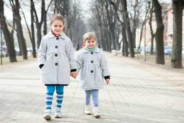 two cute girls on  street in  early spring day.