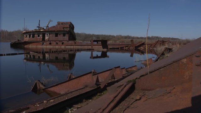 Graveyard of ships on the river.  Many rusty barges and boats in water. Chernobyl zone of alienation