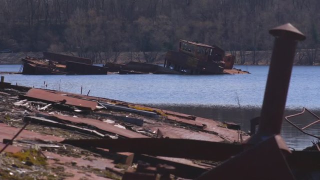 Graveyard of ships on the river.  Many rusty barges and boats in water. Chernobyl zone of alienation