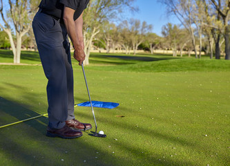 Fototapeta premium Man golfer putting green late afternoon golf round
