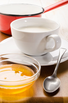 warm milk in a cup and acacia honey in small bowl