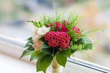 Wedding bouquet on window sill. Bride's traditional symbolic accessory. Floral composition with red...