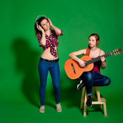 Two young women having fun, listening to music with headphones a