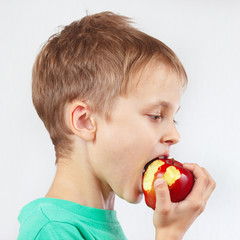 Young boy in a green shirt eating a juicy red apple