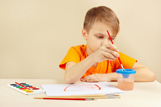 Little artist in an orange shirt painting colors