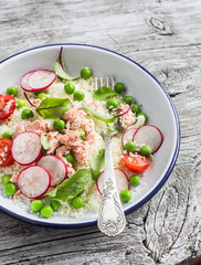 Delicious healthy food - salad with cous cous, fresh vegetables and baked salmon. On a light  wooden rustic background
