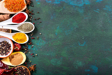 various spices in spoons on old green background