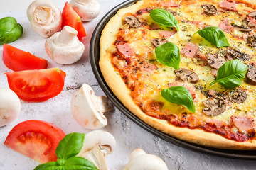 Delicious pizza with mushrooms, ham and basil.