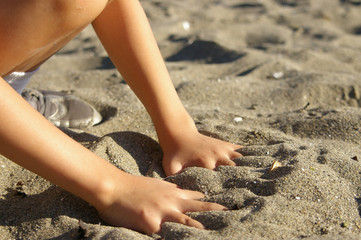 Young boy playing in the sand at the beach on a sunny summer day. 