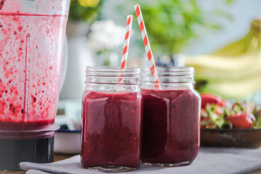 Berry smoothie on wooden table in sunny kitchen