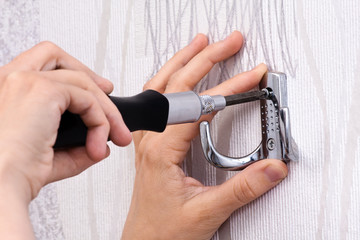 hands screwing hook with black screwdriver