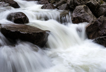Small water fall with water pouring over rocks. Long exposure