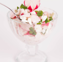 Cottage cheese with radish and chives in a cup eaten with a fork