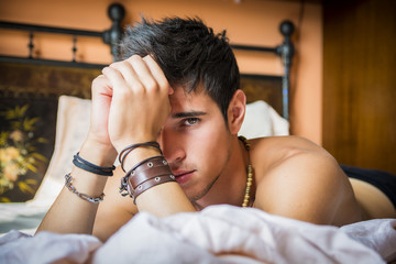 Shirtless sexy male model lying alone on his bed