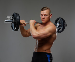 Fototapeta na wymiar Shirtless muscular man holds barbell.