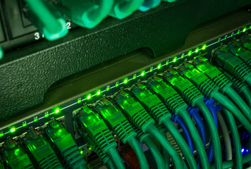 Close up of green network cables connected to switch glowing in the dark