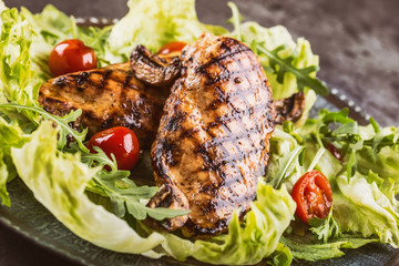 Grilled chicken breast in different variations with lettuce salad cherry tomatoes .mushrooms herbs cut lemon on a wooden board or teflon pan. Traditional cuisine. Grill kitchen.