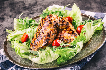 Grilled chicken breast in different variations with lettuce salad cherry tomatoes .mushrooms herbs cut lemon on a wooden board or teflon pan. Traditional cuisine. Grill kitchen.