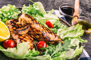 Grilled chicken breast in different variations with lettuce salad cherry tomatoes .mushrooms herbs cut lemon on a wooden board or teflon pan. Traditional cuisine. Grill kitchen.